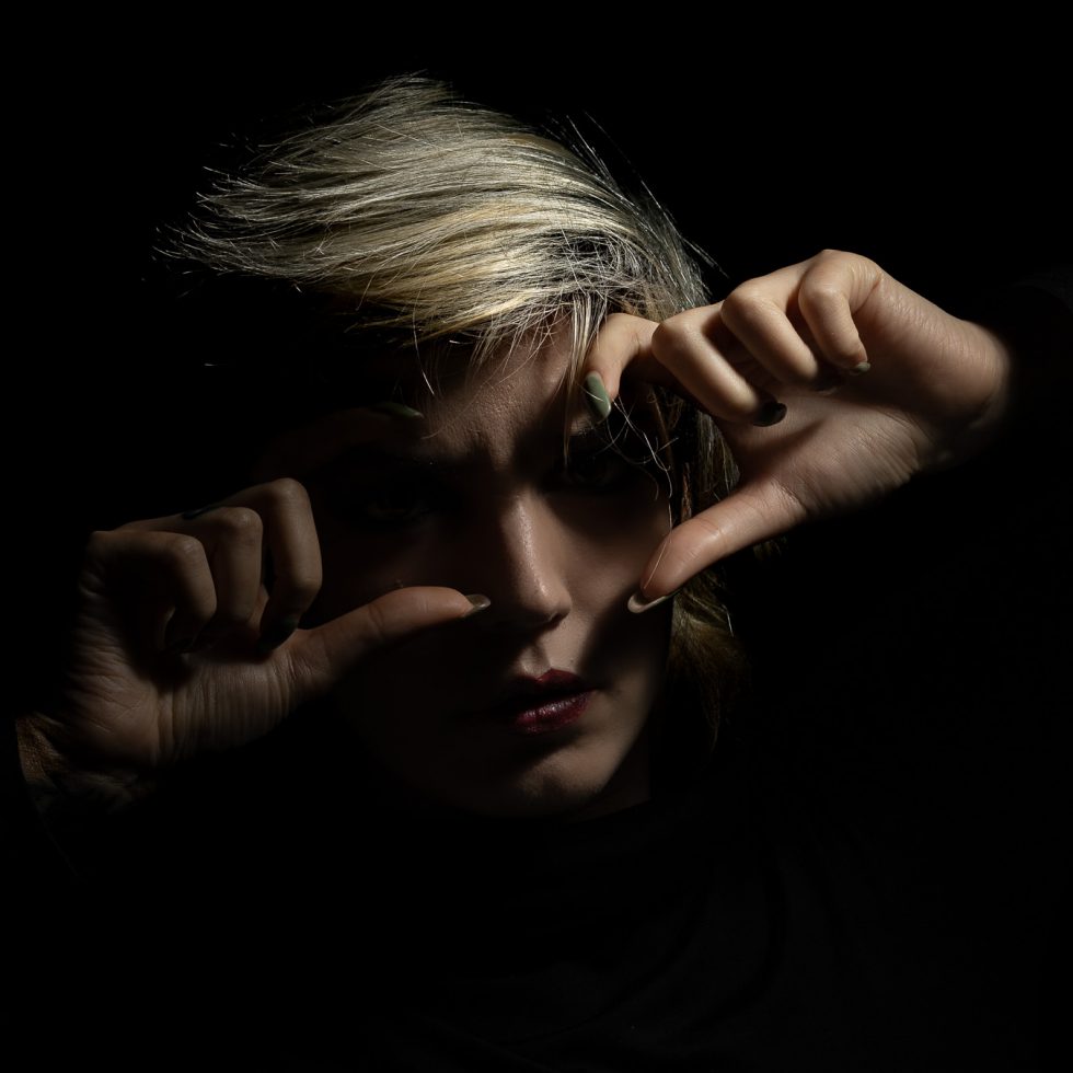 Rossana, modelo italiana, retrato artístico en clave baja con juego expresivo de manos y luz dramática sobre fondo negro.